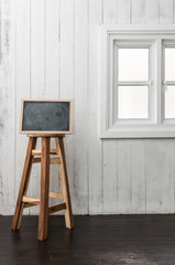 Chalkboard and round wooden chair on a dark timber wood floor, n