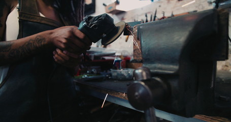 Woman mechanic grinding a piece of metal in a workshop - Powered by Adobe