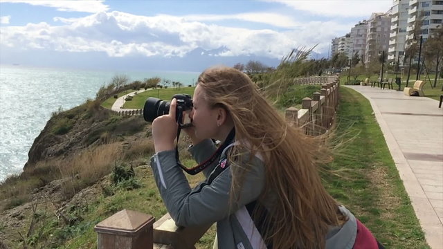 A tourist makes a horizon photograph in Antalya. Girl photographer shooting photos with an SLR camera. 