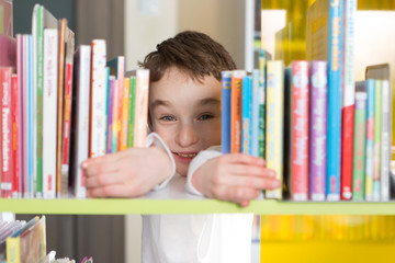 Cute boy reading book in library
