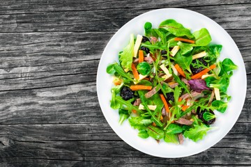 mixed lettuce, spinach, carrot, ham, cheese and prunes salad , top-view