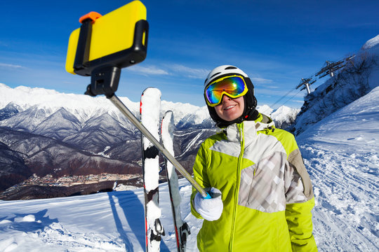 Smiling skier woman take selfie with stick