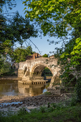 Fototapeta premium Leaves framed view to medieval Aylesford bridge and river in Kent, England