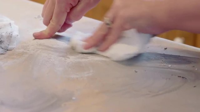 Detail of cook's hands cleaning a baking tray with scouring powder and paper towels.  Originally recorded in 4K, UHD.