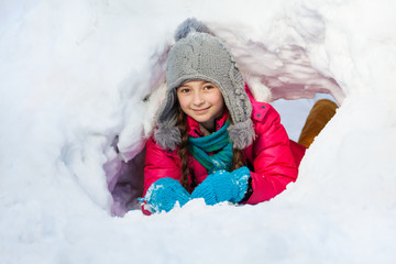 Girl is playing outside in tunnel she dug of  snow