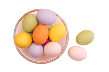 Colored eggs on a bowl on a white background seen from above