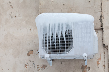 Air conditioner with frozen ice and icicles. Cooling, cold concept image. Aged wall background.