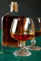 Two glasses of brandy and bottle on a green table top