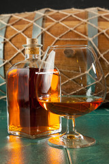 Glass of brandy and bottle on a green table top