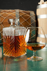 Glass of brandy and a carafe on a green table top