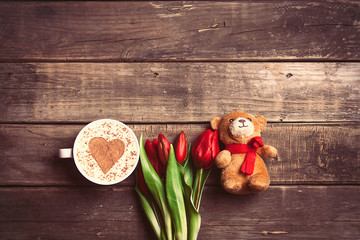 bunch of tulips, teddy bear and cup of coffee on the table