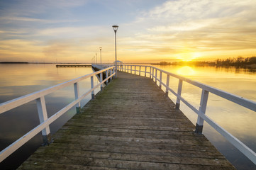 Obraz na płótnie Canvas wooden, white pier on the bay at sunset
