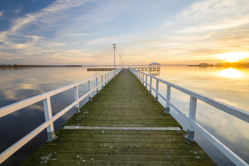 wooden, white pier on the bay at sunset