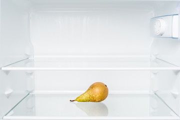 Green pear in empty refrigerator. Diet and hunger concept
