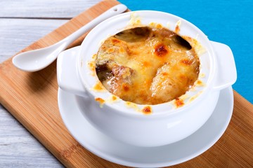 french onion gratin soup in a white pot, close-up