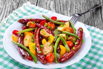 Grilled sausage with garlic, potato, cherry tomatoes, green beans, top-view