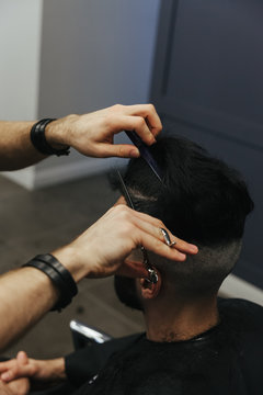 Male barber combing and shaving hair of a male client