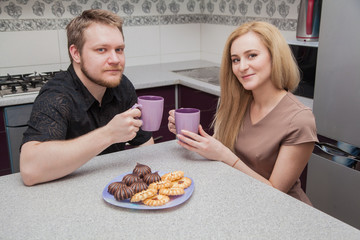 man and woman in the kitchen drinking a hot drink