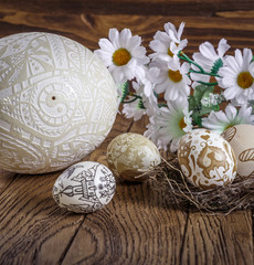 decorated big ostrich egg. hand painted Easter eggs and fresh flowers, on a wood background