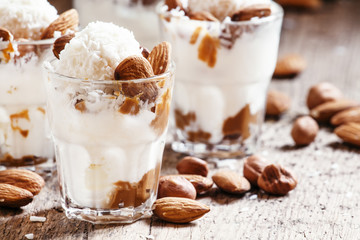 Ice cream with peanut sauce, hazelnuts and almonds in glasses, s