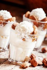 Ice cream with peanut sauce, hazelnuts and almonds in glasses, s