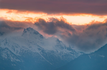 Fototapeta na wymiar Panorama montano, montagne innevate tramonto, tramonto montano con cielo rosso e giallo