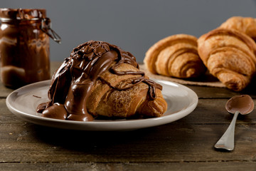 Sweet croissant with chocolate on rustic background