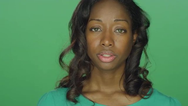Beautiful African American woman looking sad, on a green screen studio background