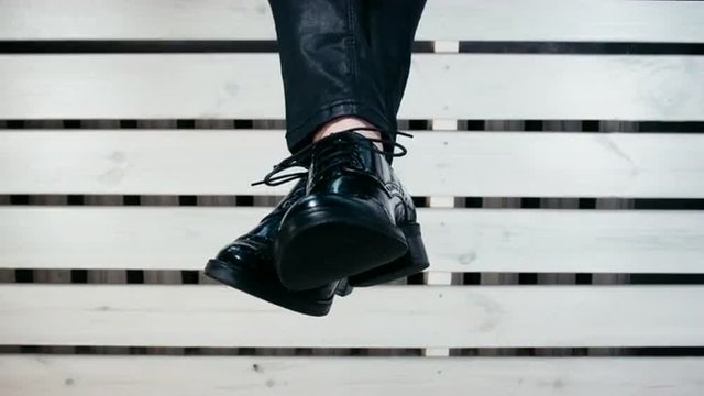 Girl swinging legs against wooden background. 4K 60 FPS. Shot with Blackmagic URSA Mini