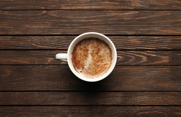 Cup of coffee on wooden table, top view