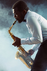 Naklejka na ściany i meble African American jazz musician playing the saxophone against colorful smoky background
