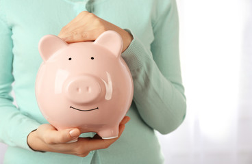 Obraz na płótnie Canvas Woman holding piggy bank in hand. Financial savings concept