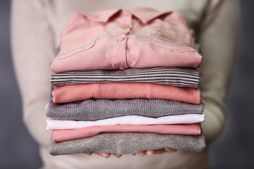 Woman holding washed and dried clothes on grey background