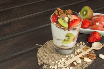 Preparing healthy breakfast for kids. Yogurt with oatmeal, fruit, nuts and chocolate. Oatmeal for breakfast. Preparing diet meals. A healthy diet for athletes.
