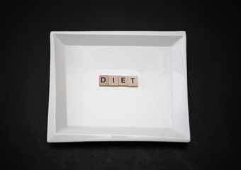 Closeup view of stylish square ceramic plate with word diet made of wooden small squares