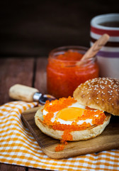 Fried egg with red caviar on a bun