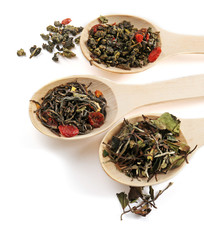 Fototapeta premium Variety of tea leaves in wooden spoons, isolated on white