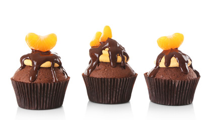 Three tasty cupcakes with slice of mandarin and chocolate, isolated on white