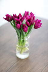 Beautiful bouquet of purple tulips on wooden table at living room