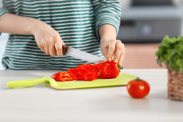 Young woman cutting vegetables for salad in the kitchen