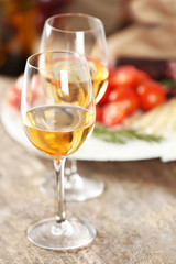 Glasses of wine with food on wooden table closeup