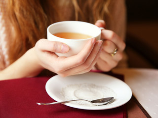 Woman with cup of tea on table in cafe or restaurant