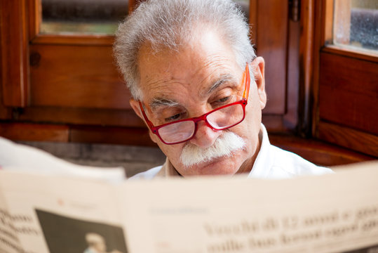 Senior Reading Newspaper At Home