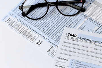 1040 Individual Income Tax Return Form with  black rimmed glasses isolated on the white background, close up