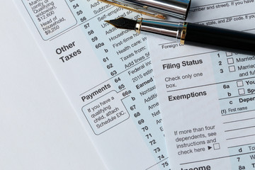 1040 Individual Income Tax Return Form for 2015 year with a pen to fill on the white desk, close up