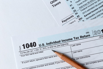 Obraz premium 1040 Individual Income Tax Return Form for 2015 year with a pencil to fill on the white desk, close up