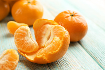 Fresh delicious unpeeled tangerines and peeled with slices on the light-blue wooden board, close up