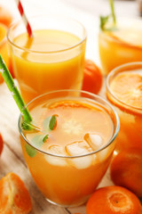Tangerine cocktails with ice and mint on a white wooden board, close up