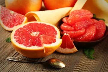 Juicy pieces of grapefruit with fresh mint on wooden table, close up