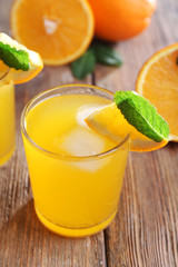 Two orange juices with ice and orange on wooden table background